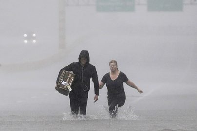 Two people walk down a flooded section of Interstate 610 in floodwaters from Tropical Storm Harvey on Sunday, Aug. 27, 2017, in Houston, Texas. (AP Photo/David J. Phillip)