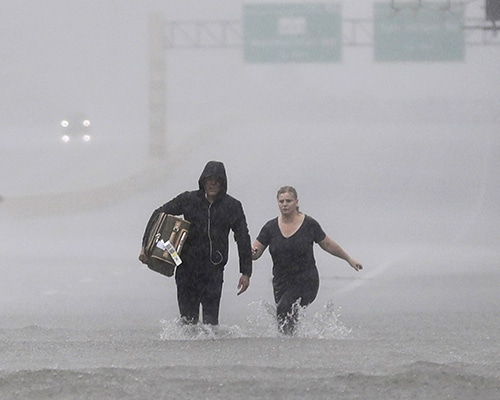 Two people walk down a flooded section of Interstate 610 in floodwaters from Tropical Storm Harvey on Sunday, Aug. 27, 2017, in Houston, Texas. (AP Photo/David J. Phillip)