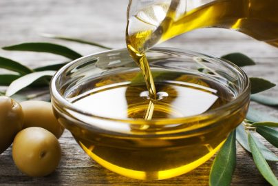 Bottle pouring virgin olive oil in a bowl close up