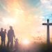 Silhouette father mother and two son looking for the cross on autumn sunrise background