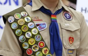 IMAGE VIA time.com - Merit badges and a rainbow-colored neckerchief slider are affixed on a Boy Scout uniform outside the headquarters of Amazon in Seattle. The U.S. organization, which now welcomes girls into the program and allows them to work toward the coveted Eagle Scout rank, announced Tuesday, May 7, 2024, that it will change its name to Scouting America as it focuses on inclusion. (AP Photo/Ted S. Warren, File)
